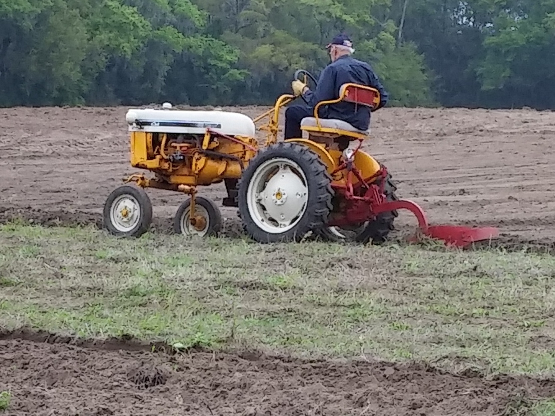 person plowing a field on an antique tractor