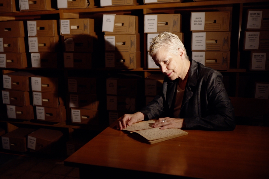 Woman on stage, sifting through documents