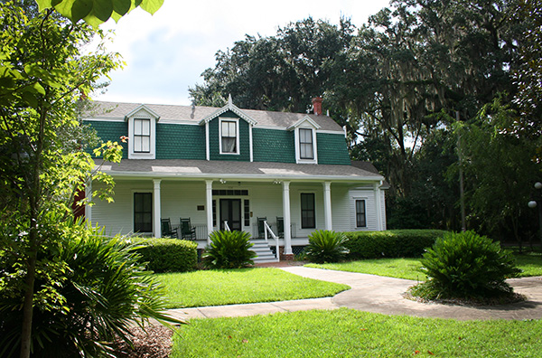 A green and white cottage welcomes visitors with on open front porch in Alachua County, Florida. 