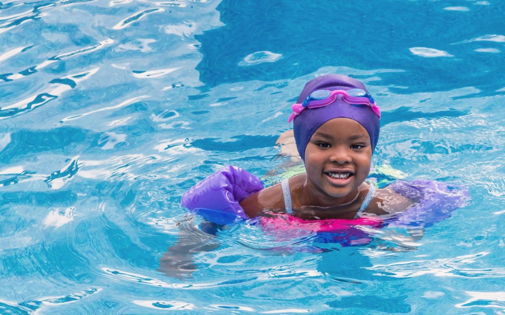 a girl in a pool wearing goggles and a swim cap